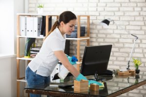 woman cleaning glass desk